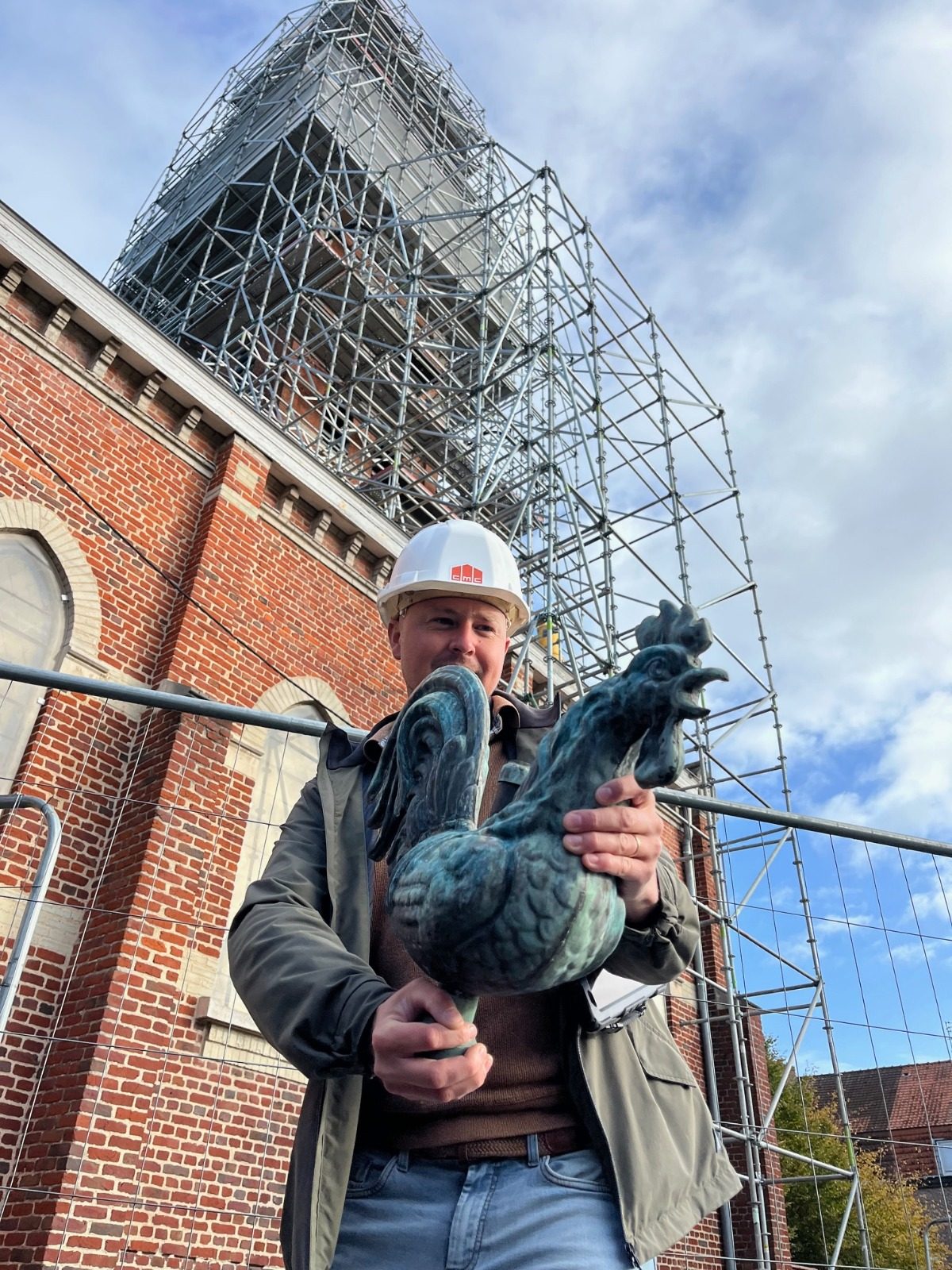Charles Bocquet, casque CMC, tenant le coq du clocher devant l'église Notre-Dame de Lourdes échafaudée