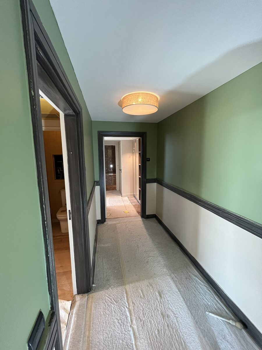 Couloir de circulation peint en vert d'eau avec plinthes laquées noir