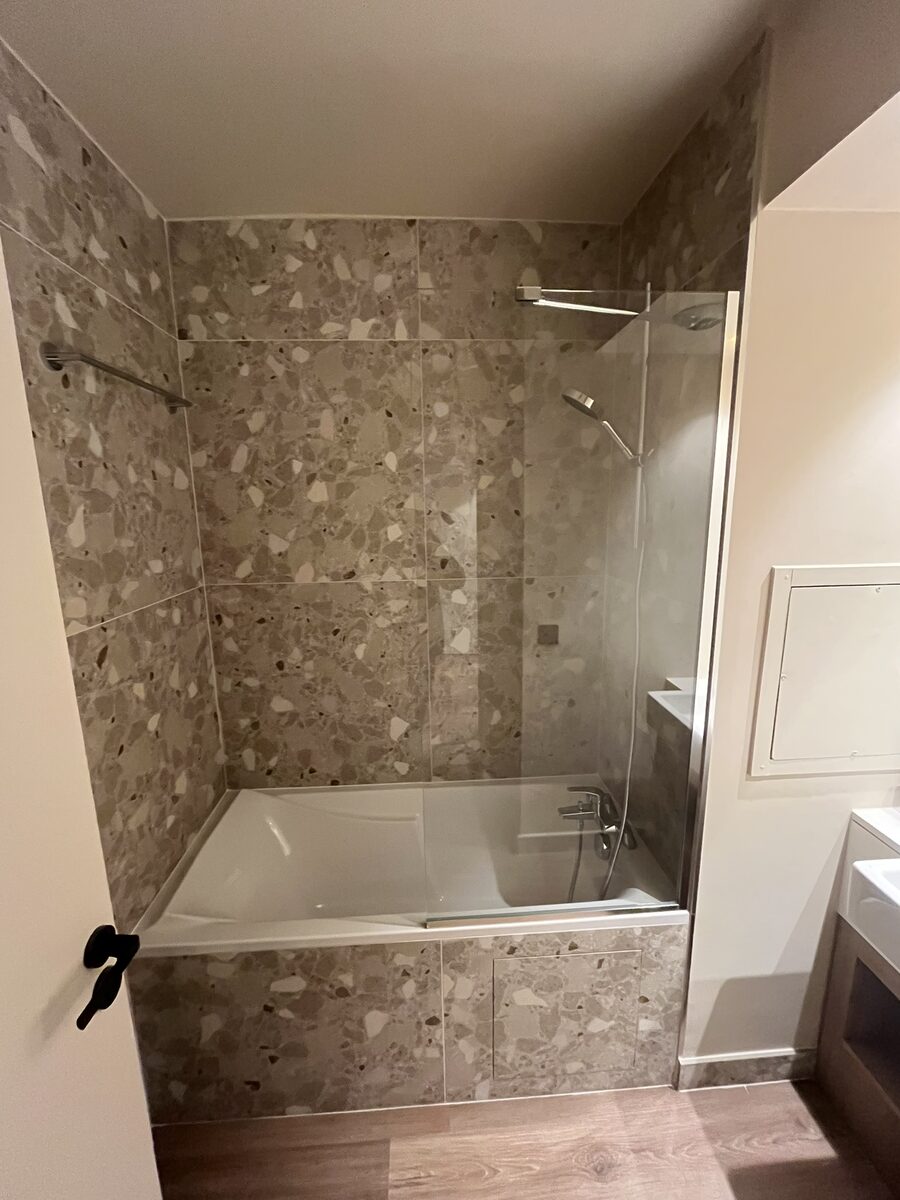 Salle de bain avec faïence terrazzo, baignoire et paroi vitrée