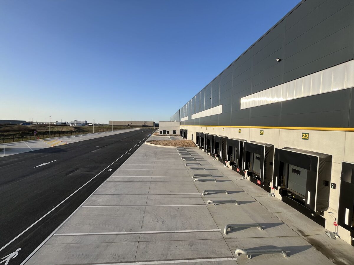 Façade principale de la plateforme logistique au coucher du soleil avec alignement des quais et bureaux d'exploitation