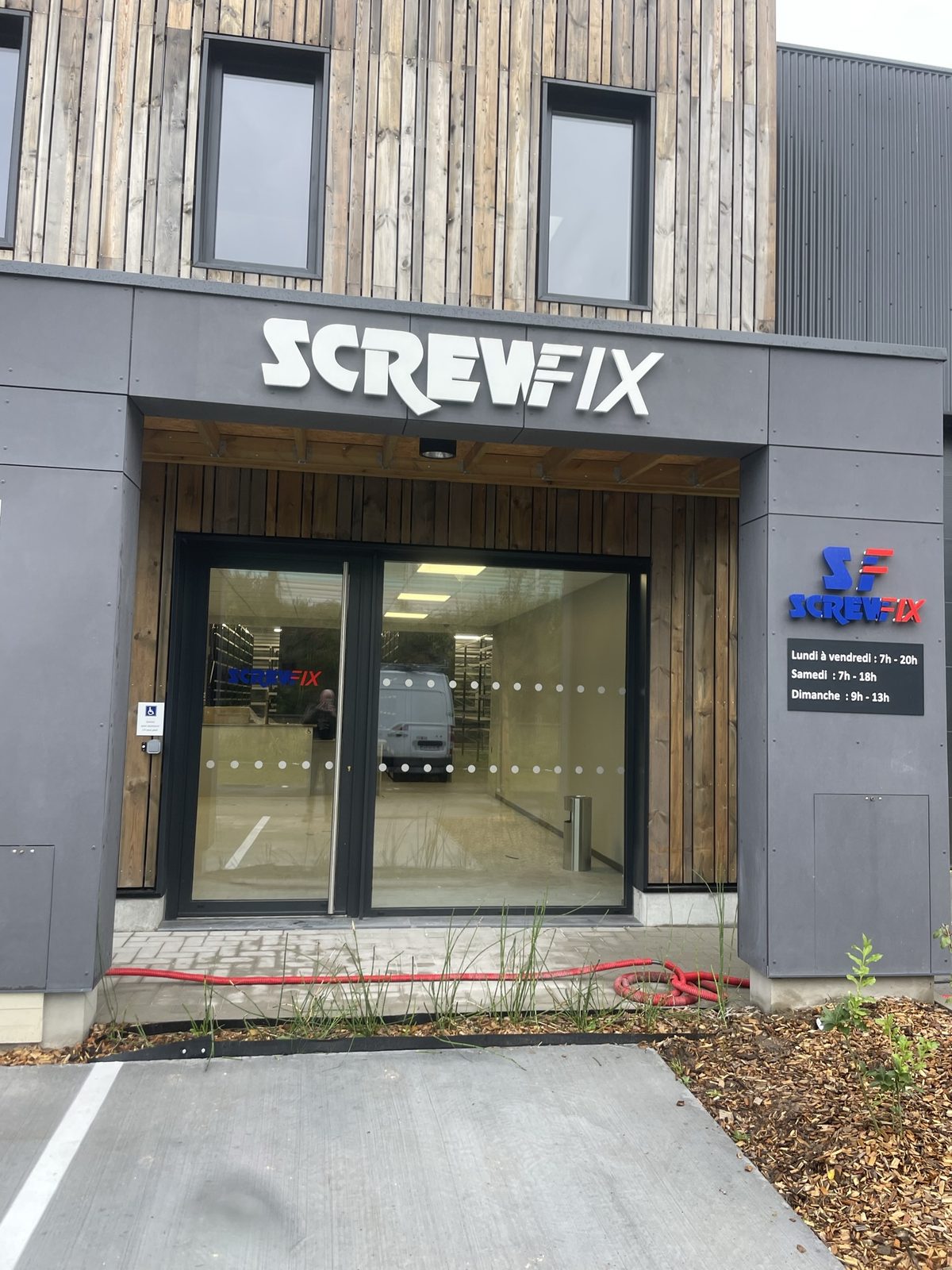 Entrée du magasin Screwfix avec enseigne et horaires
